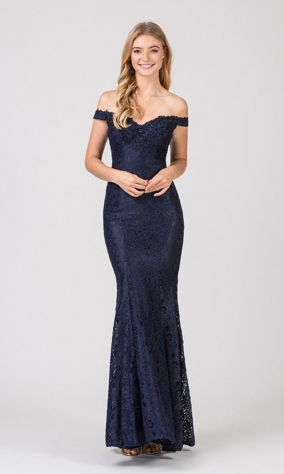 A woman stands gracefully against a plain light background, wearing the navy Long Prom Dress: Eureka 8030, an off-the-shoulder, floor-length lace gown.